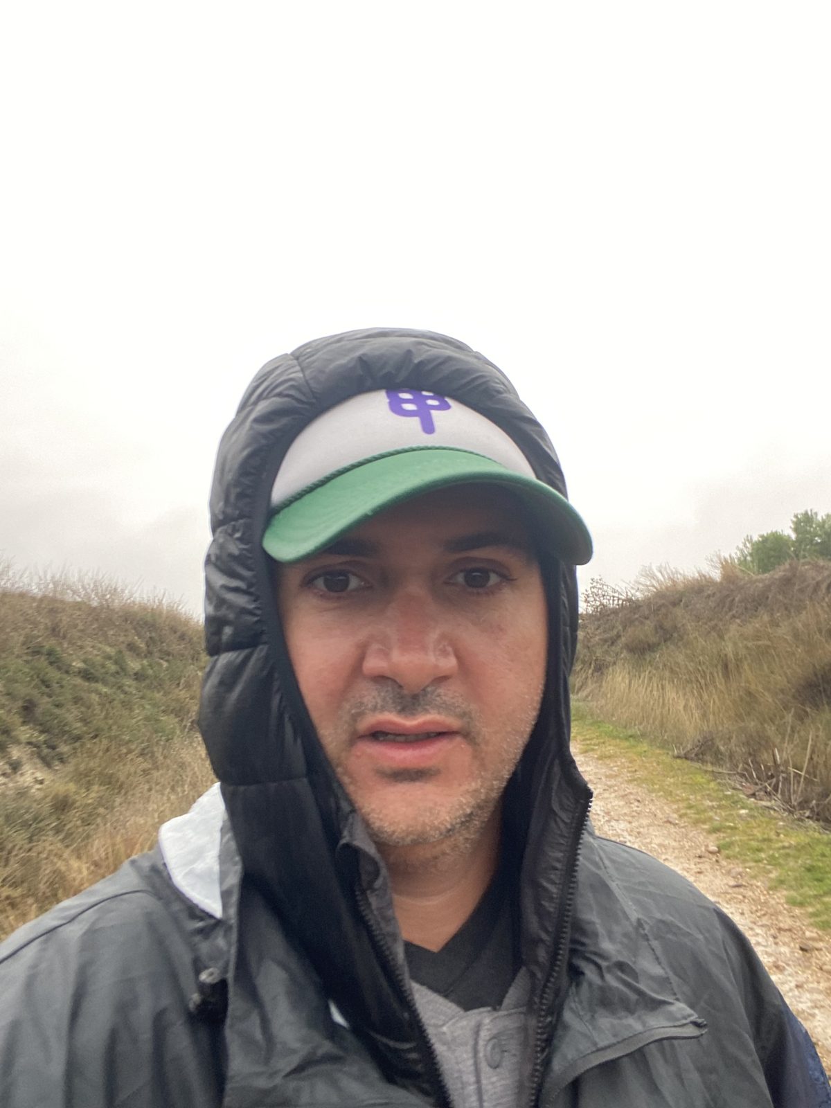 Selfie in a rain hood and cap on a misty, wet trail