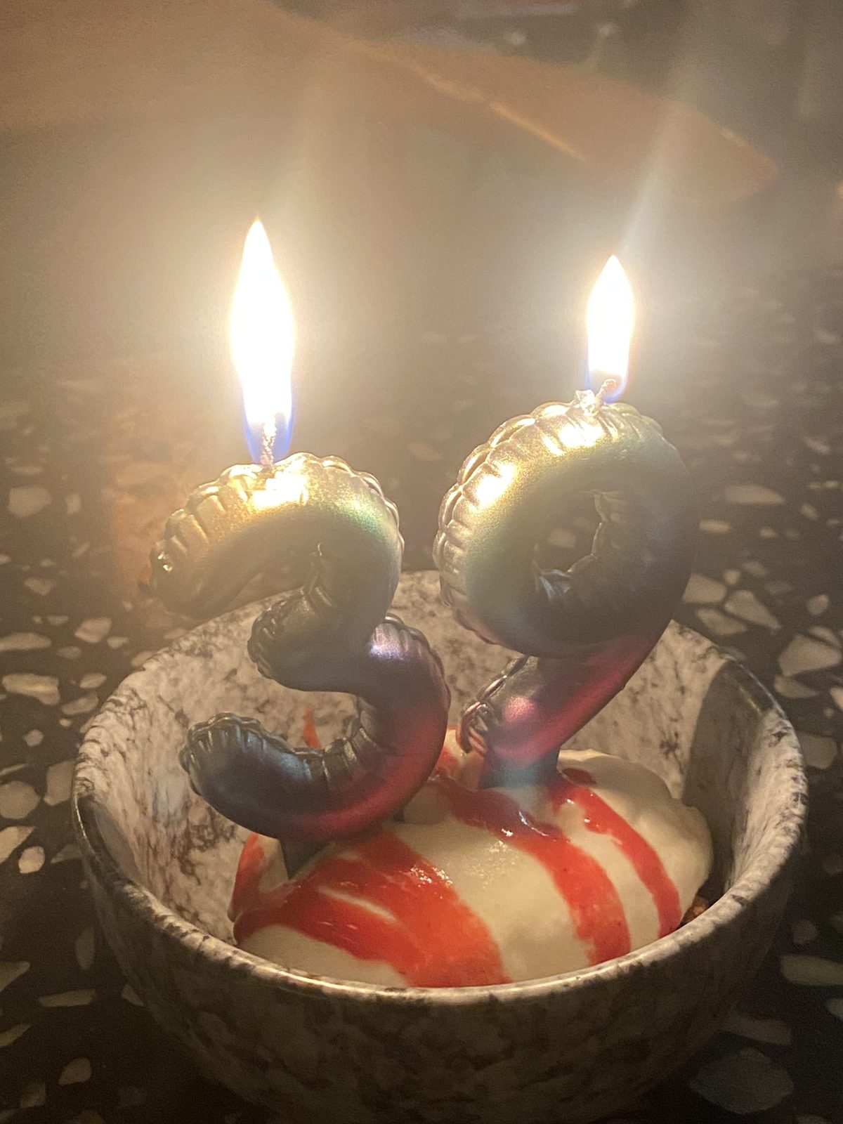 A scoop of ice cream in a bowl topped with lit number 3 and 9 birthday candles