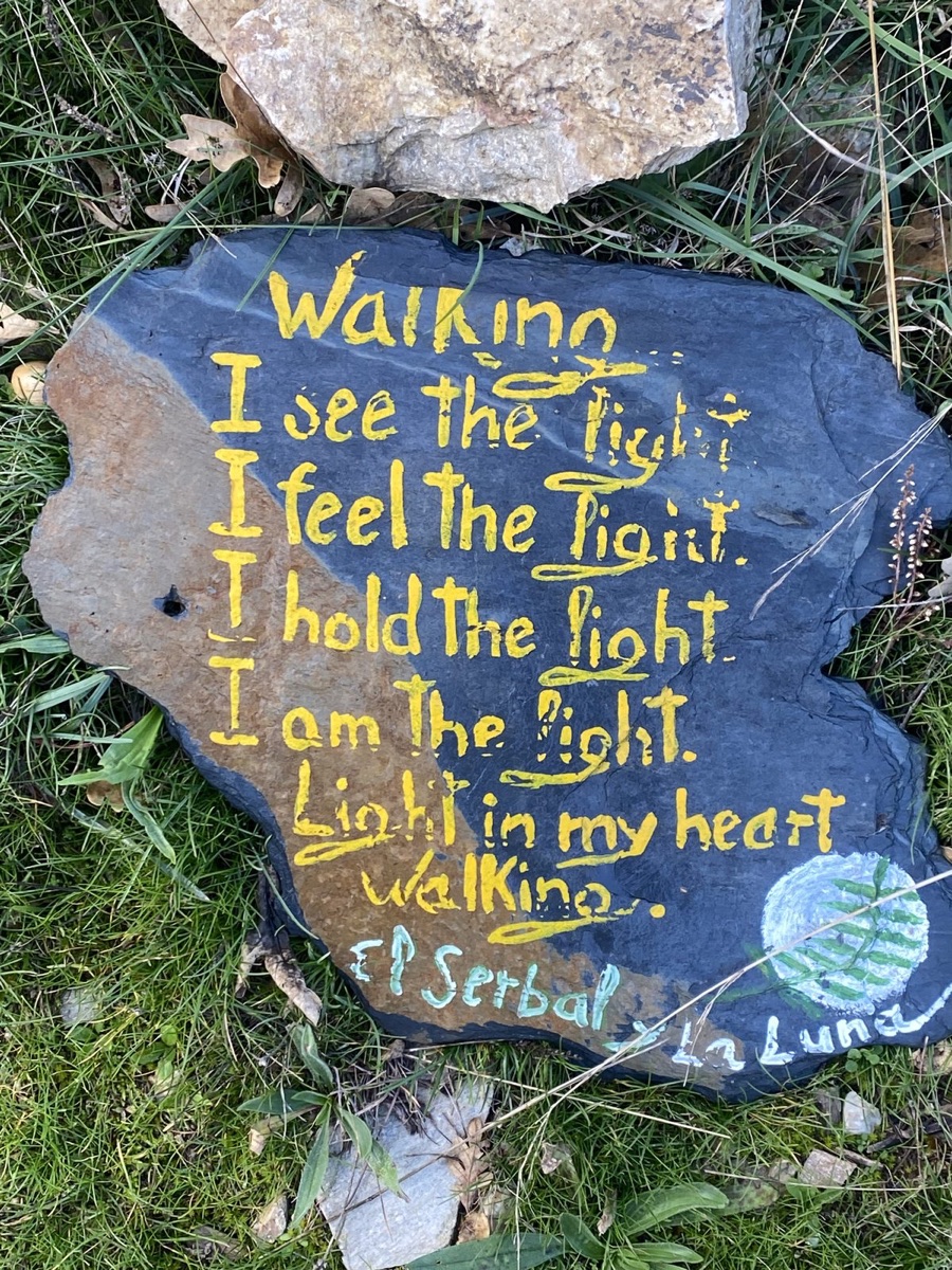 Yellow handwriting painted on a slate stone about walking and light