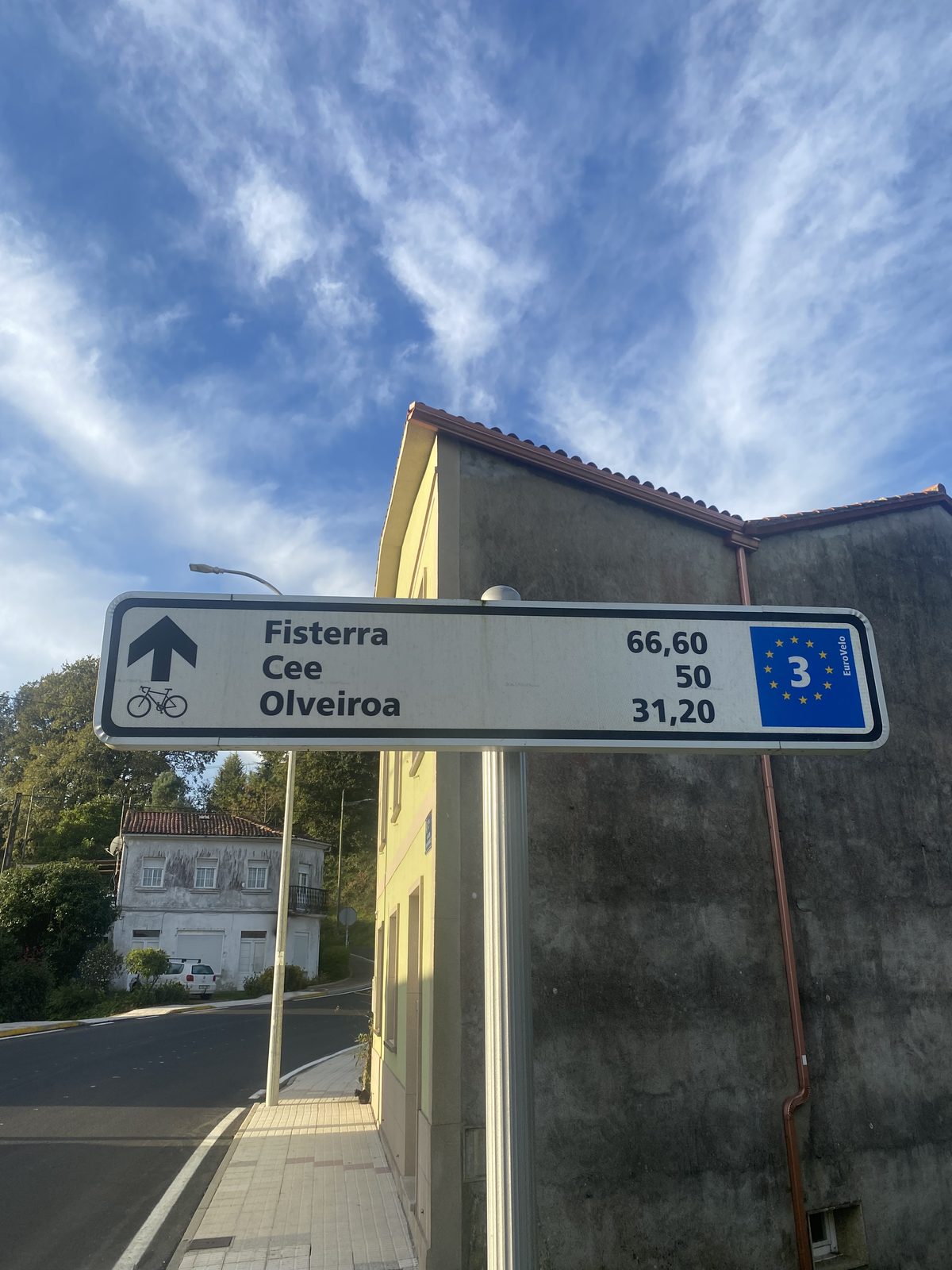 A road sign pointing to Fisterra 66.60 km with a bicycle symbol