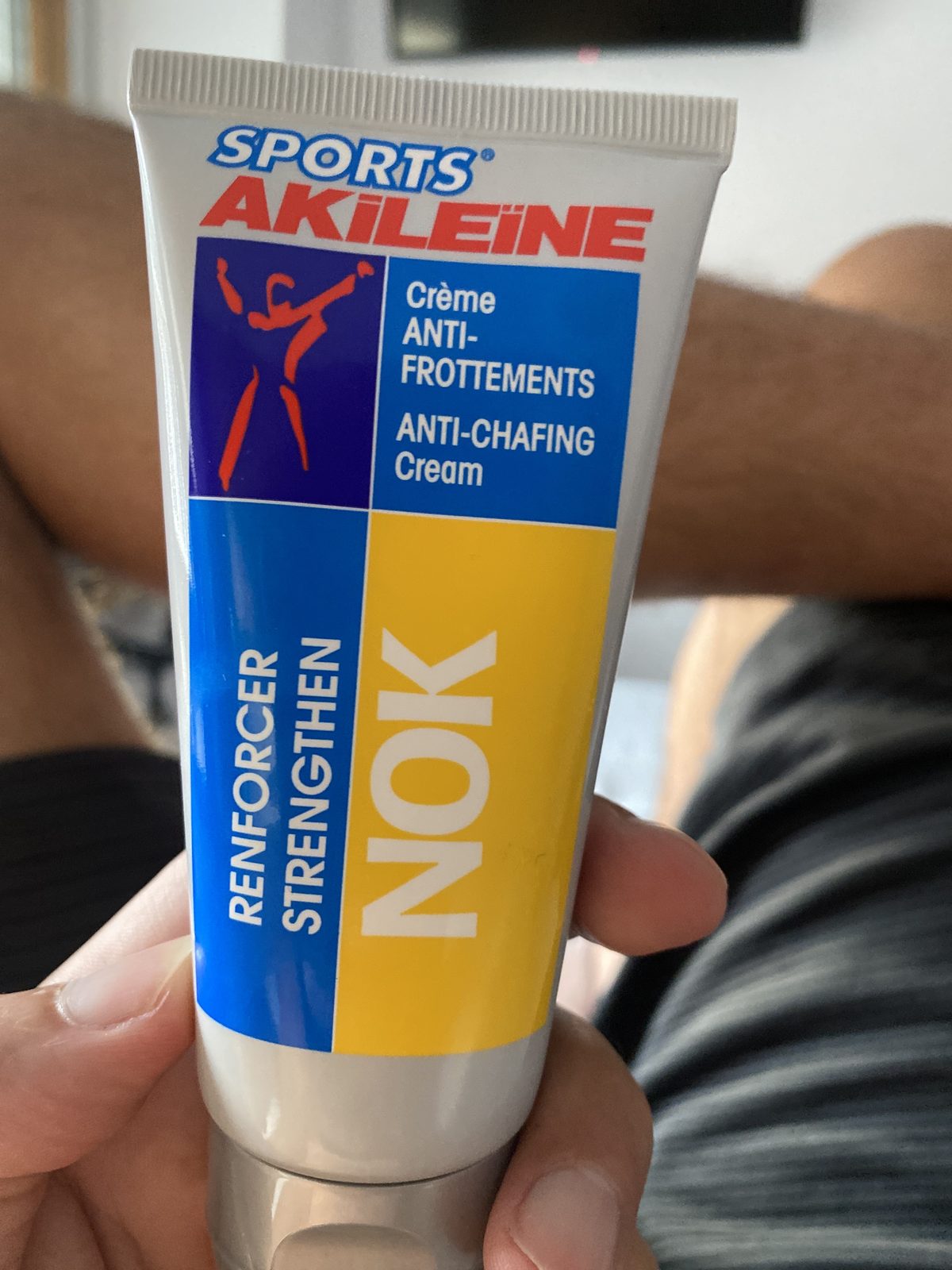 A tube of Sports AKILEINE NOK anti-chafing cream held in one hand